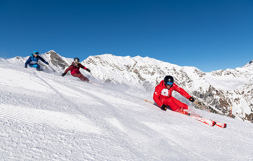 <p>Zwei Skifahrer mit Skilehrer auf Skipiste</p>
